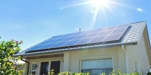 Solar panels on roof, modern house, blue sky.